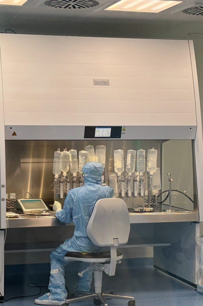 Mitarbeiter sitzt in Schutzkleidung im Reinraum und produziert 